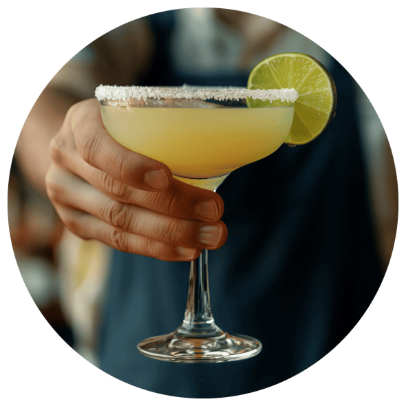 A male bartender presenting a freshly made margarita with a lime garnish.